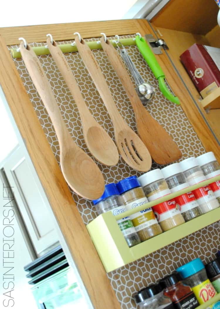 hanging utensils inside a cabinet door with spices underneath