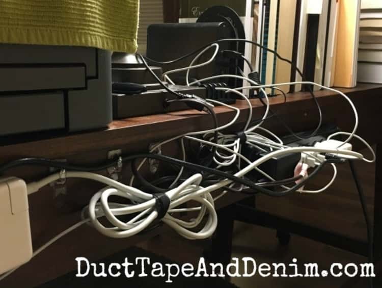 back of a wooden desk with all the cords folded in loops with velcro wraps holding them in place and command hooks keeping them neat.
