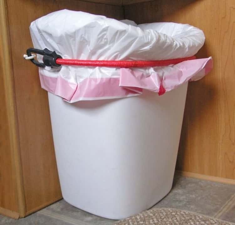 bungee cord uses - trash can held in place using command hooks and a bungee cord