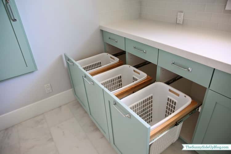 3 white laundry baskets inside green cabinets as a hidden storage place