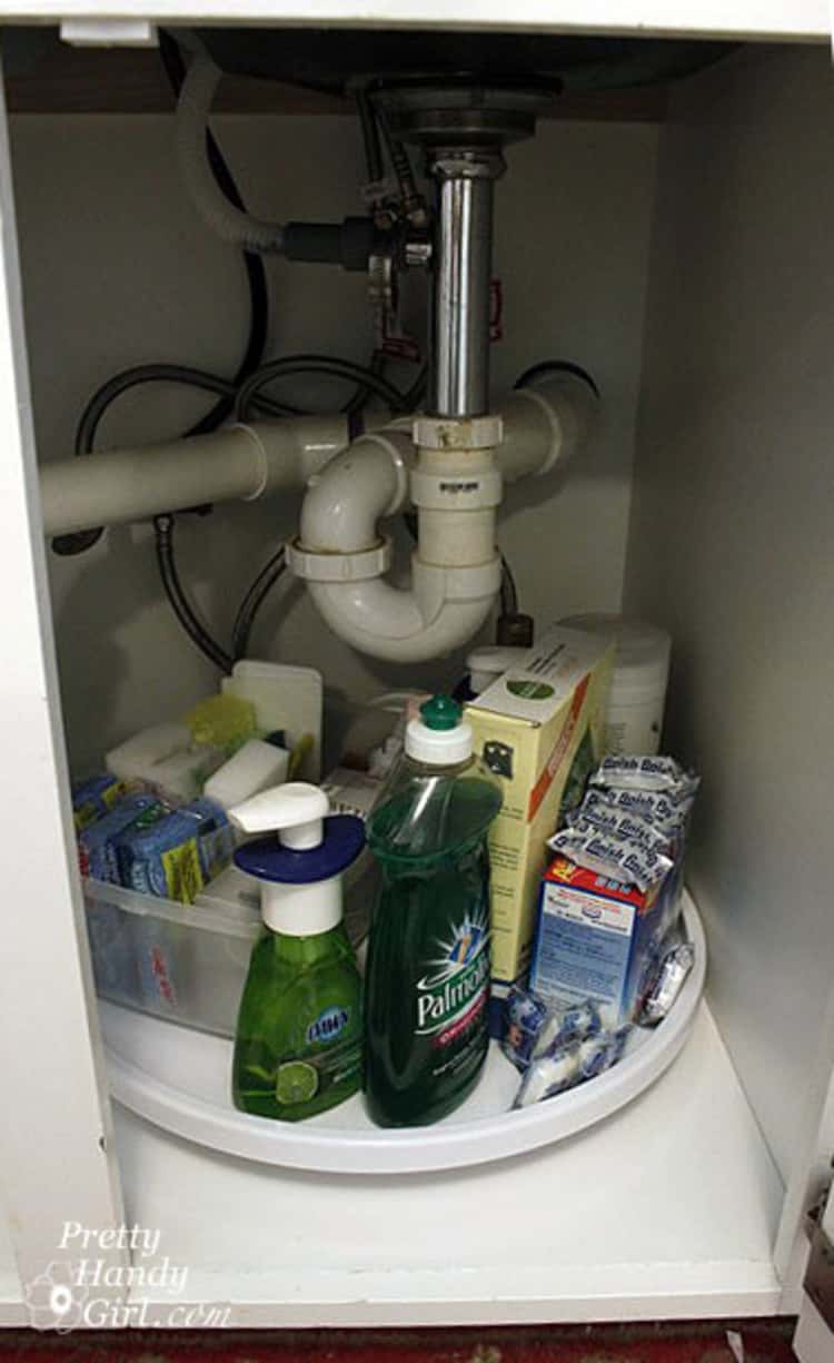 Under the kitchen sink organization with a Lazy Susan holding neatly arranged supplies. 