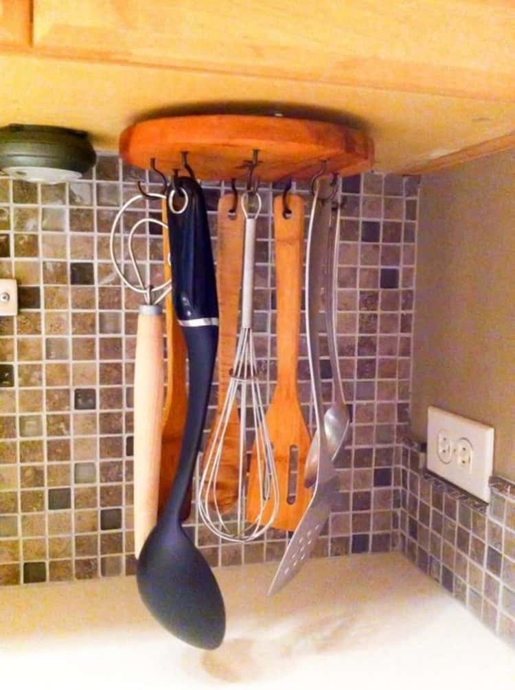 lazy susan installed under kitchen cabinet with hanging utensils on it.