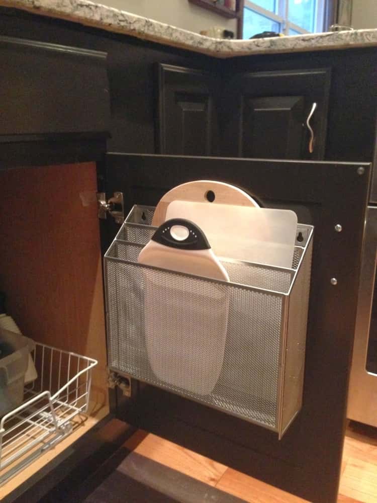 Open kitchen cabinet door showing cutting boards separately stored on a mesh magazine folder 