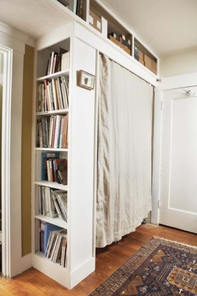 Store your clothes in a closet created with bookshelf and curtain hung between bookshelf and wall