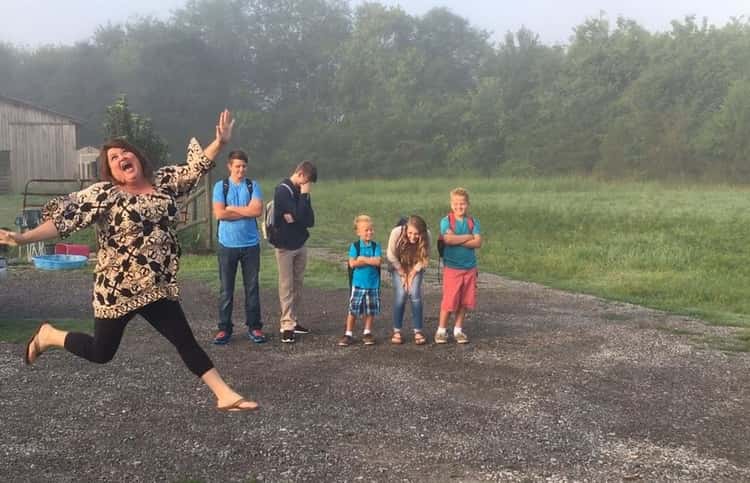 back to school photo ideas - mom jumping for joy while her kids stand in the background