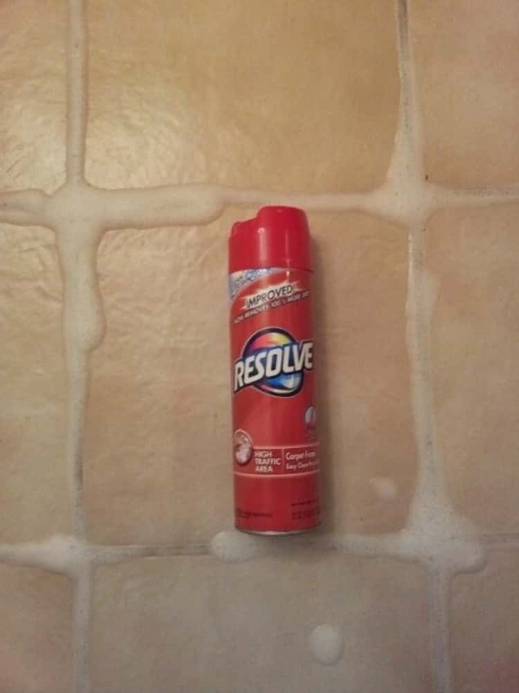 bottle of Resolve carpet cleaner on tile floor who's grout is covered with foamy solution