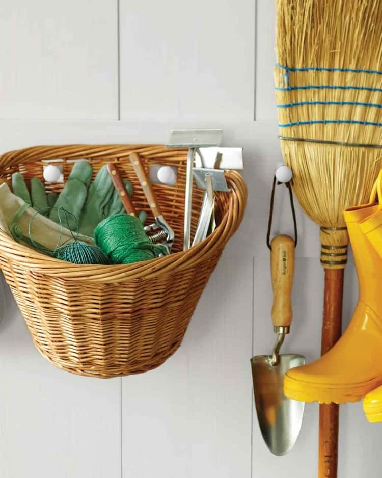 organize garden tools in a wicker basket hanging on the wall in the garage (or shed) with a broom and hand shovel and yellow boots hanging next to it