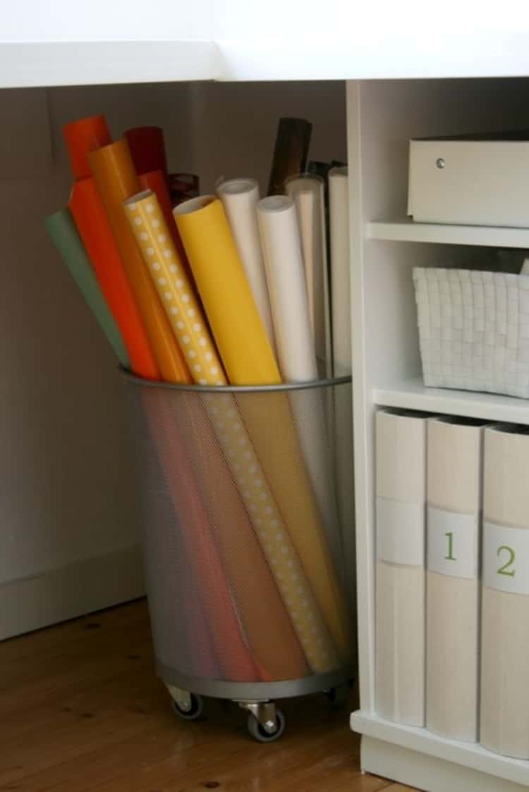 Mesh trash can on wheels used for storing gift wrap paper rolls