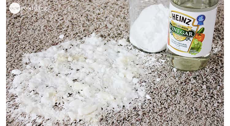 stain removal hacks - stain on carpet covered with baking soda next to a bottle of vinegar and a container with baking soda