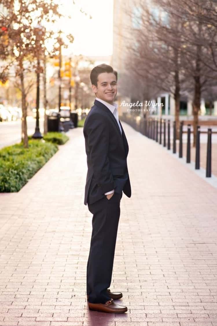 senior photo ideas for guys - guy in suit posing for photo along an empty sidewalk