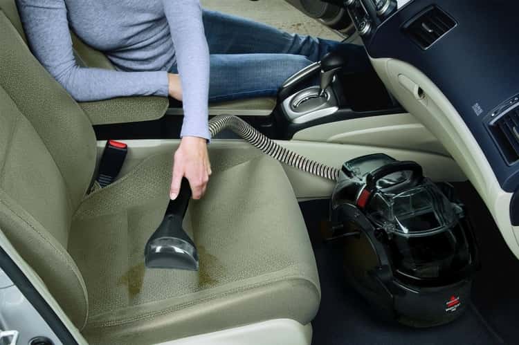 upholstery tips - person cleaning stained car seat with a carpet cleaning machine