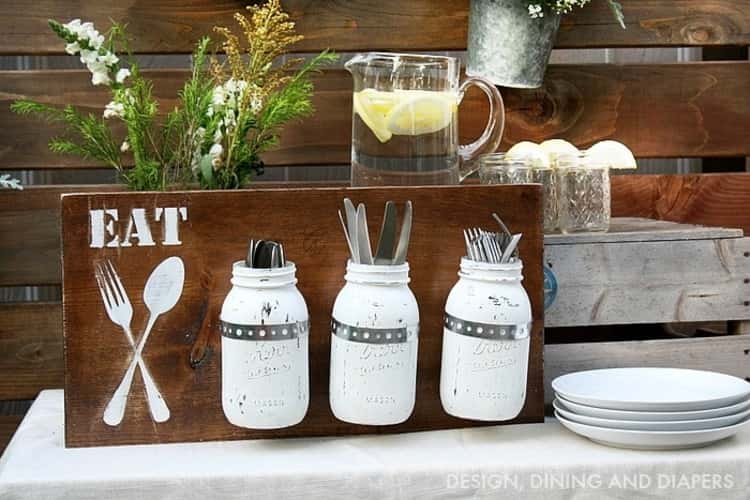 utensil organization in white painted mason jars attached to a piece of wood with EAT and utensils painted on it