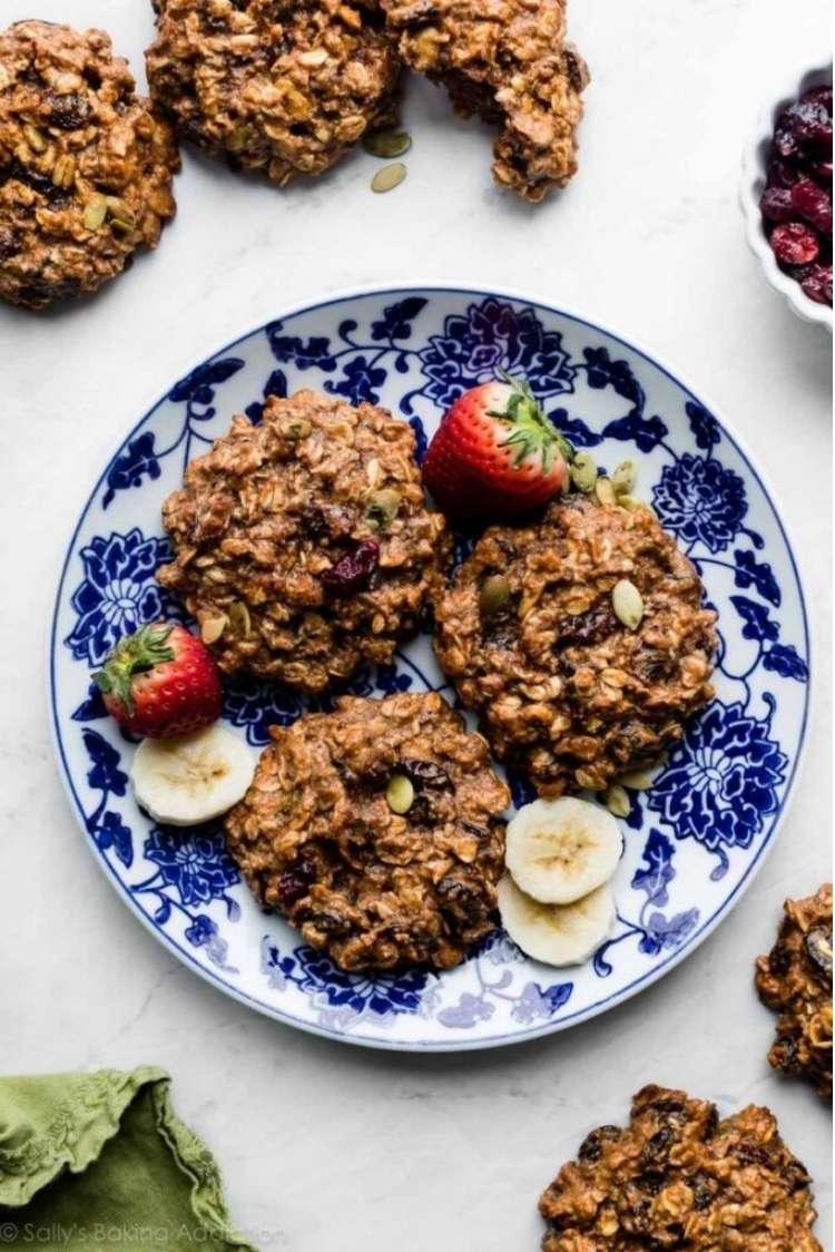 Plate with several healthy vegan breakfast cookies with fresh strawberries and banana slices