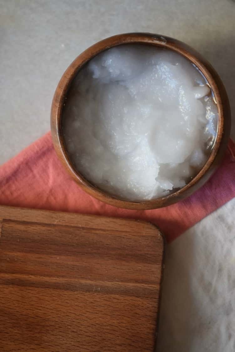 wood bowl with coconut oil next to a wood cutting board