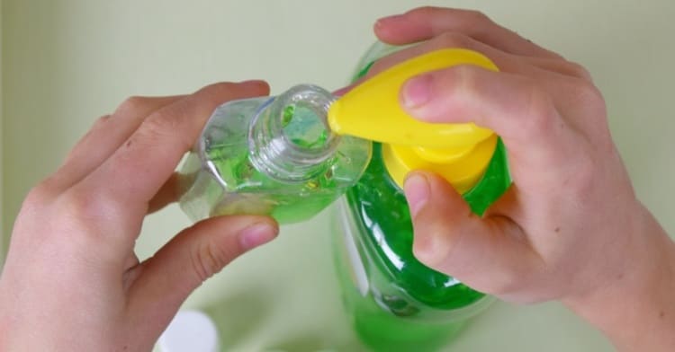 hands holding an empty plastic bottle that is being filled with aloe vera gel