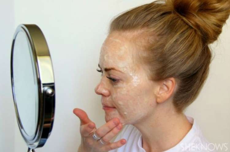 a woman putting some mask on her face in front of a mirror