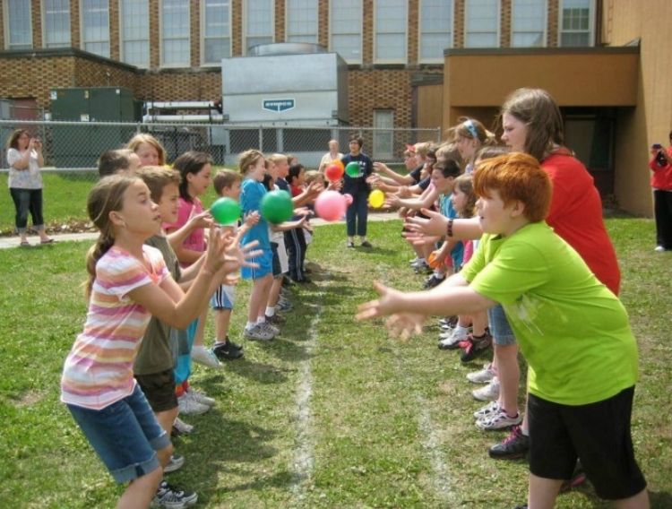 a group of kids playing pass the water balloon