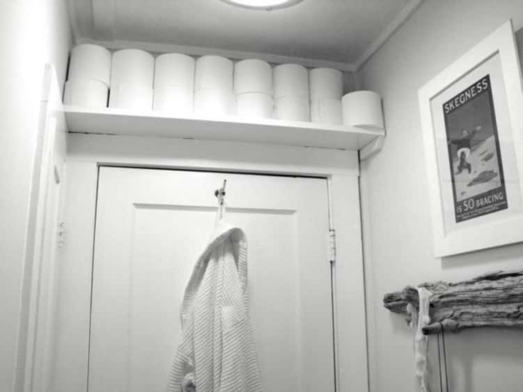 Hidden and tidy toilet paper storage in the bathroom using unused space above bathroom door and shelving