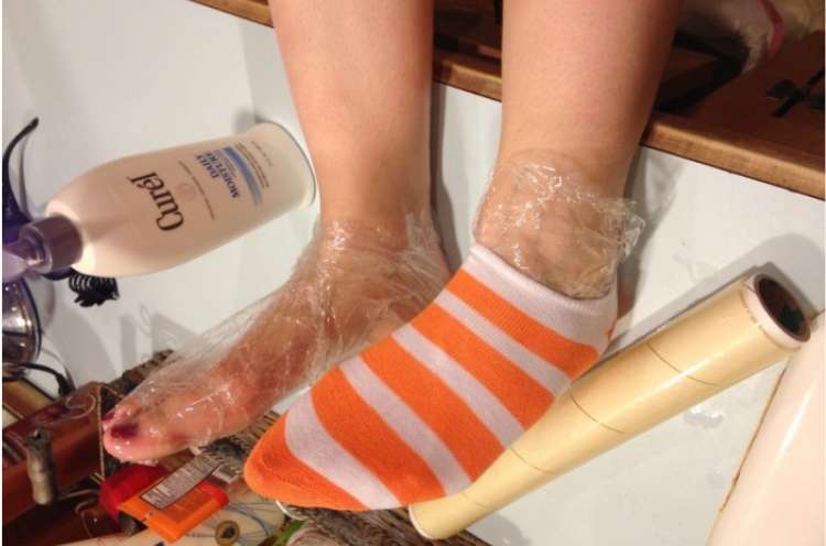 lotion on top of a sink, moisturized feet with one foot covered in plastic wrap and socks