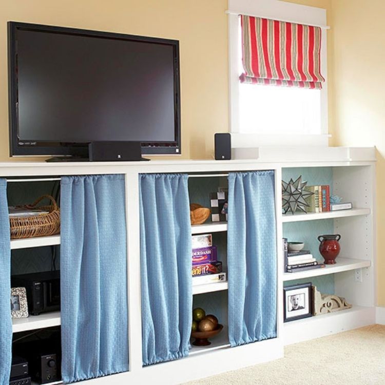 Use two simple spring rods on top and bottom of your open faced entertainment center to hang curtains to hide all your storage.