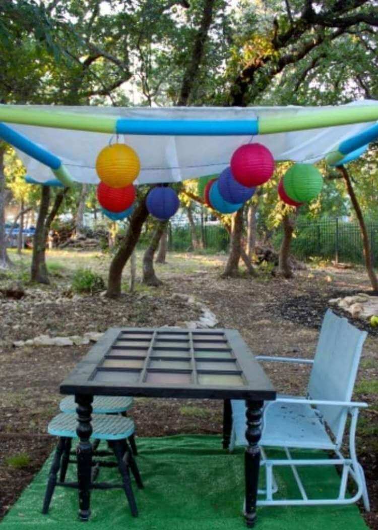 uses for pool noodles- a backward overhead canopy made of white netting and colorful pool noodles string together and suspended in the air