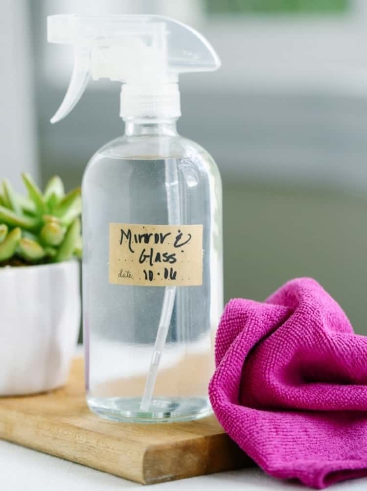 A spray bottle with glass cleaning solution and a cloth next to it.