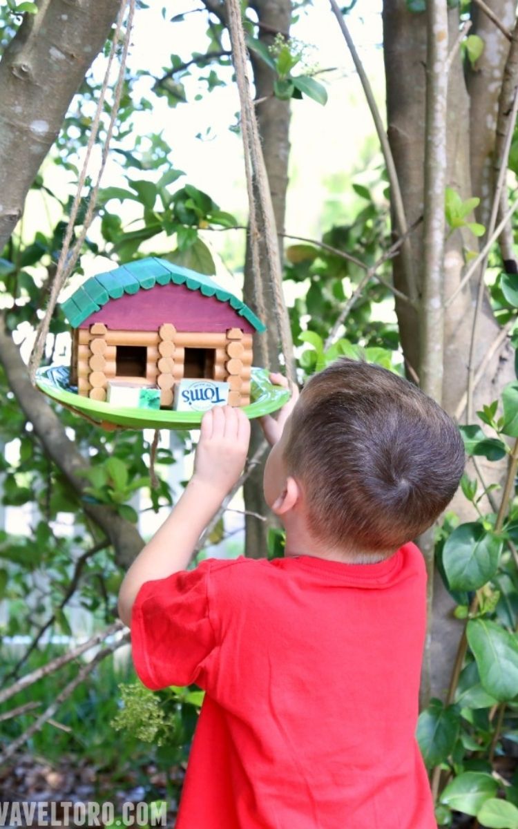 boy hanging up his Lincoln Log birdhouse