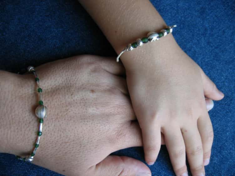 a parent and their child's hands showing matching parent/child bracelets 