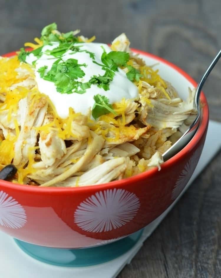 chicken taco bowl ingredients in a bowl topped with sour cream and cilantro  