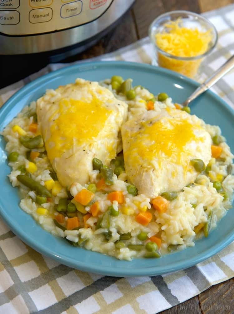 Large plate with two cheesy chicken breast on a bed of creamy vegetables and rice 