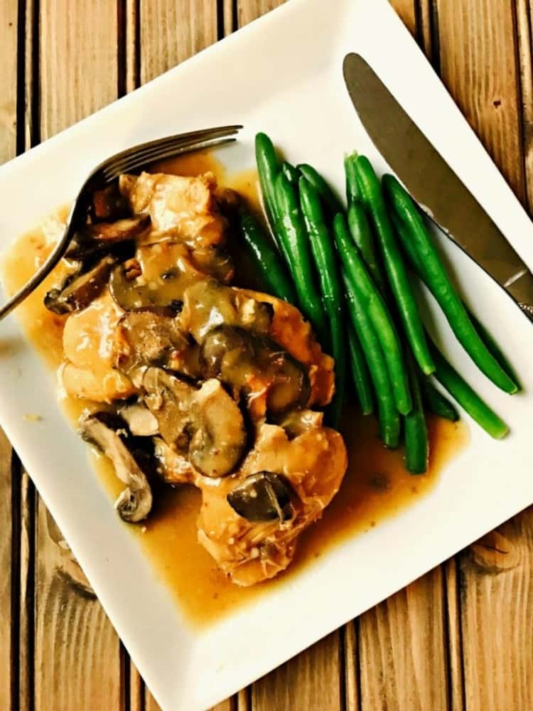 Square plate of chicken masala topped with mushrooms and served with a side of fresh green beans   