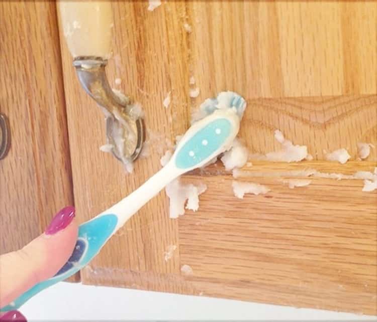 person scrubbing kitchen cabinets with a toothbrush and a mixture of baking soda and coconut oil 