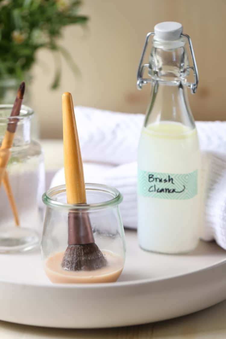 DIY natural makeup brush cleaner in use to clean a dirty makeup brush while the rest of it is in a bottle