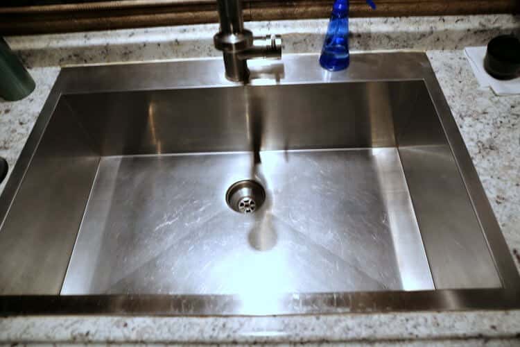 A shiny stainless steel sink cleaned with vinegar and coconut oil