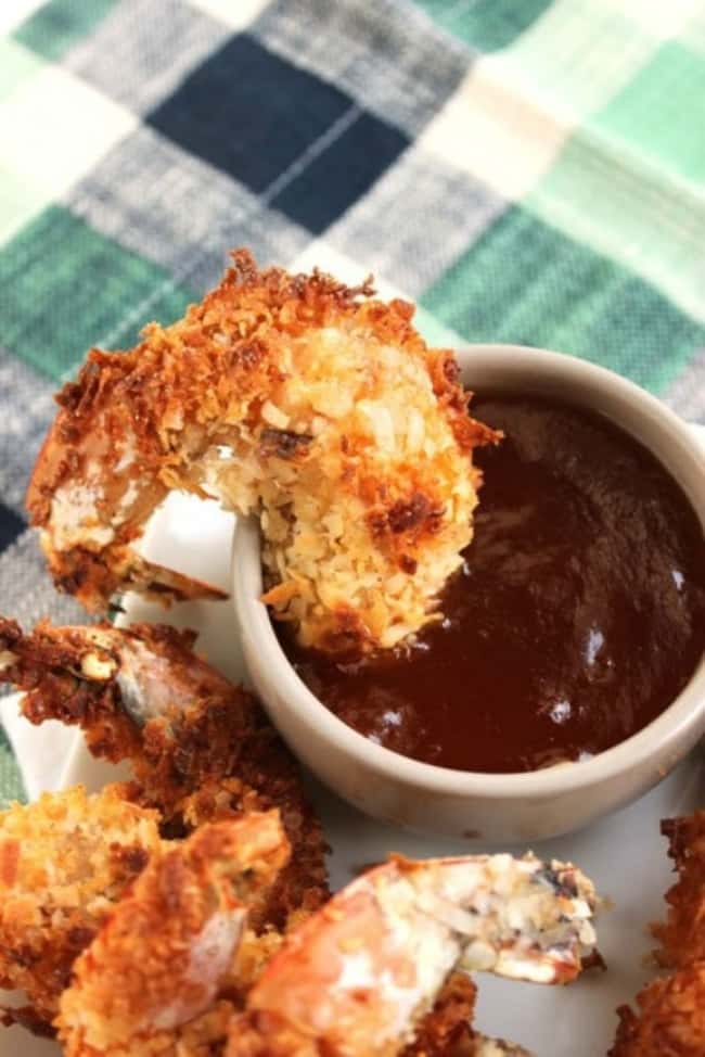 Crispy air-fryer coconut shrimp with dipping sauce on white dish.