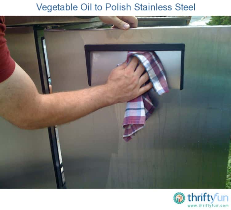 A hand applying cooking spray on a stainless steel surface.