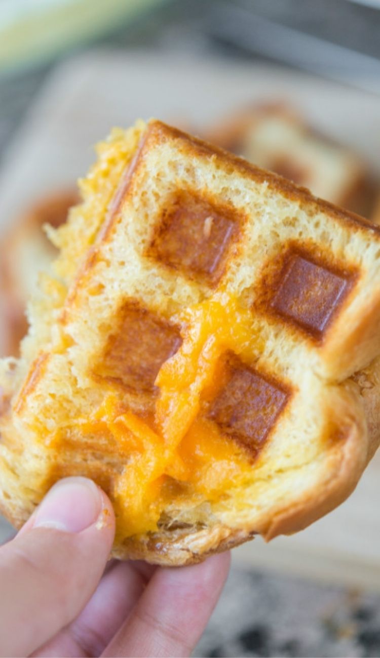 hand holding a piece of grilled cheese made in a waffle iron