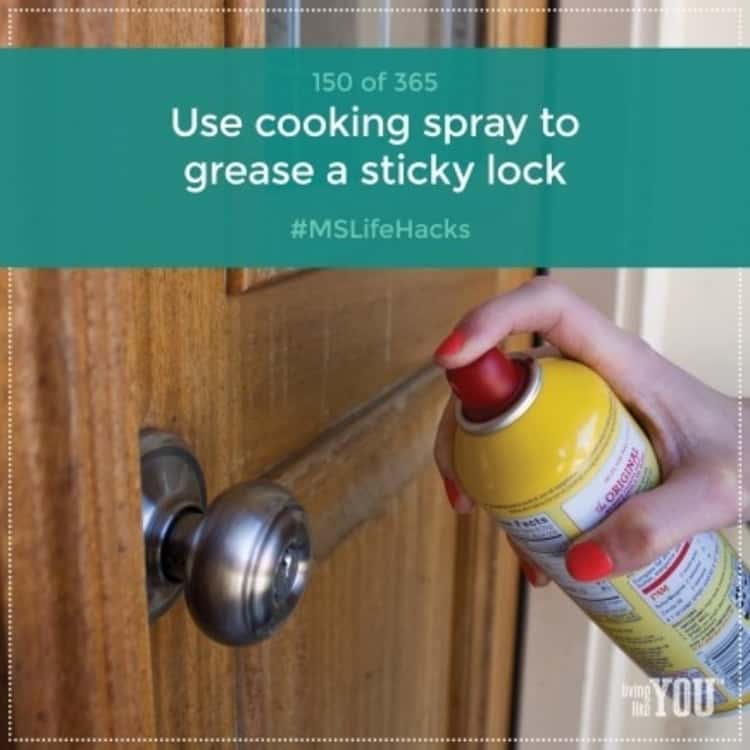 A hand spraying cooking spray on a door knob