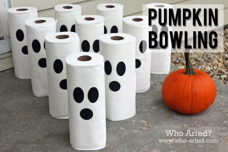 toilet paper rolls with black stickers to make for spooky faces and a pumpkin to be used in the pumpkin bowling halloween game