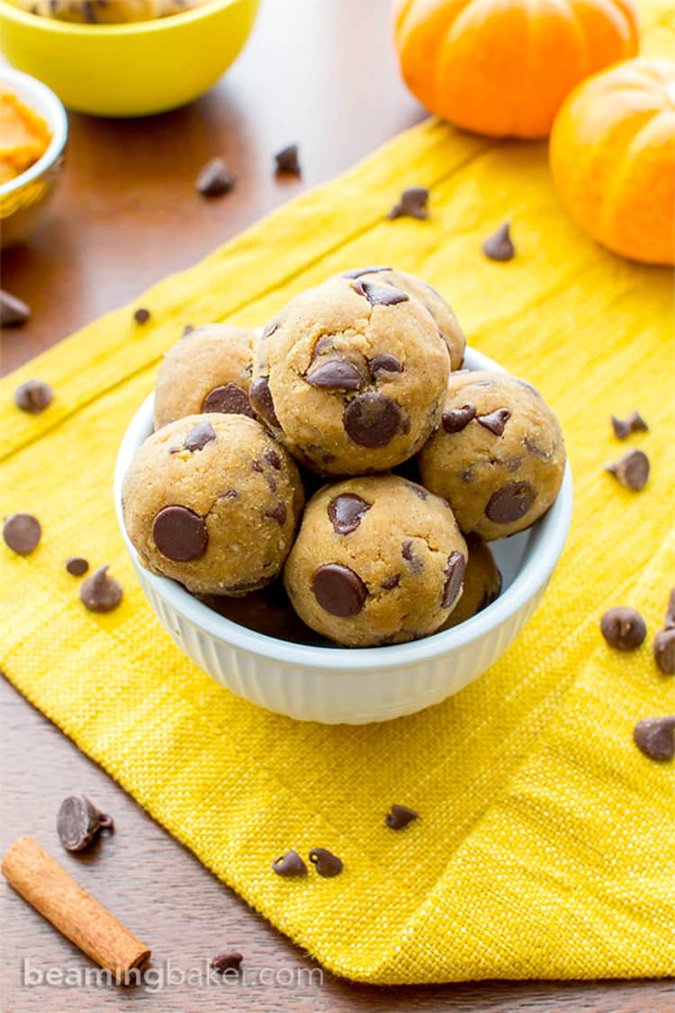 Photo of no-bake pumpkin balls with chocolate chips resting in a white ramacan. 