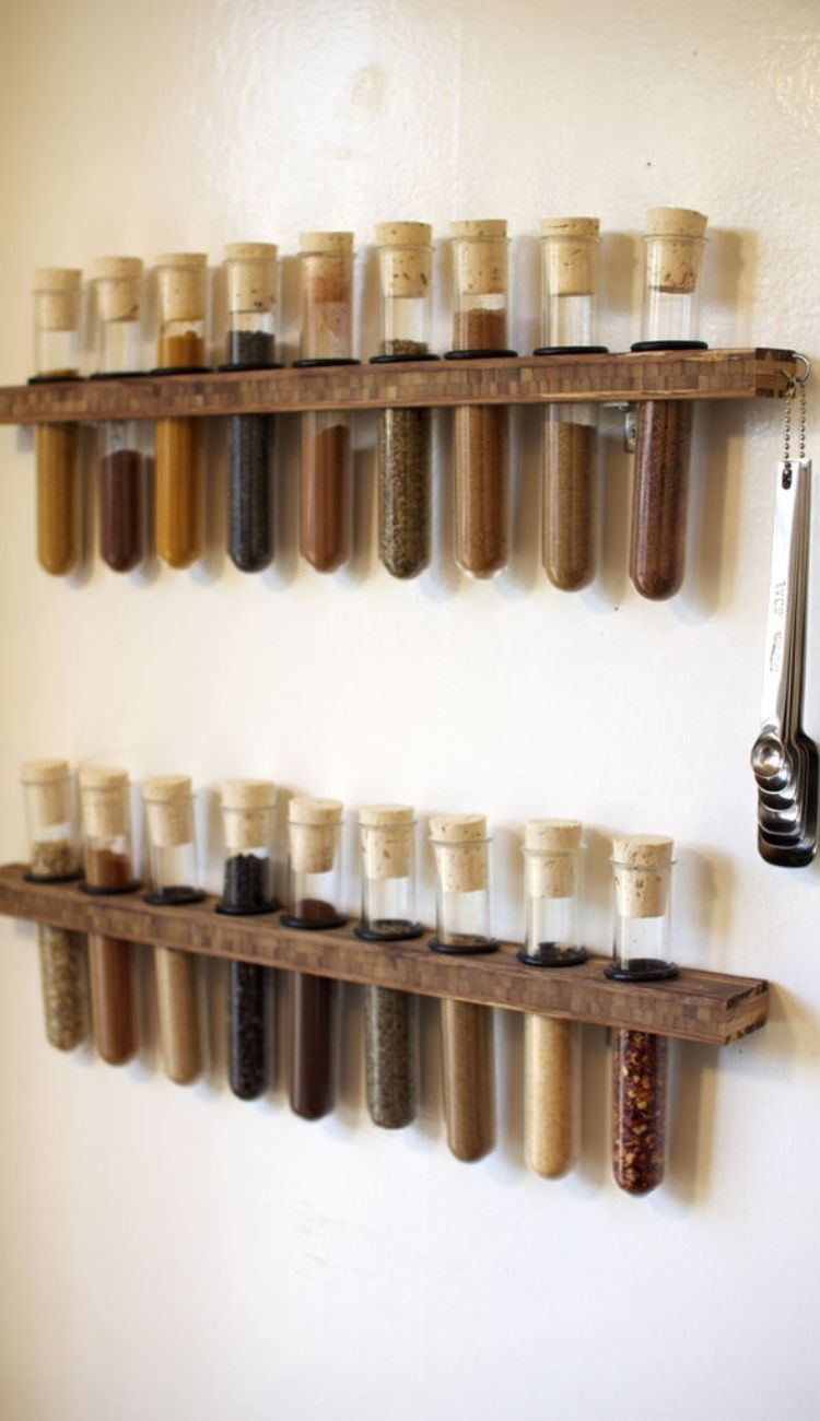 spices in test tubes lined in a wooden holder attached to a wall