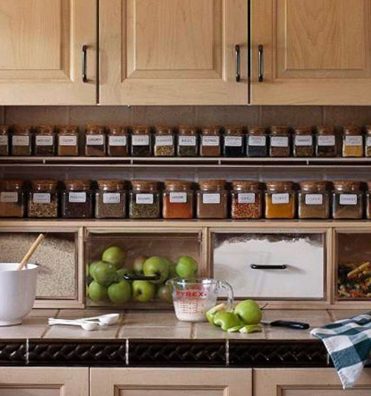 spices in matching jars lined up on a shelf under kitchen cabinets