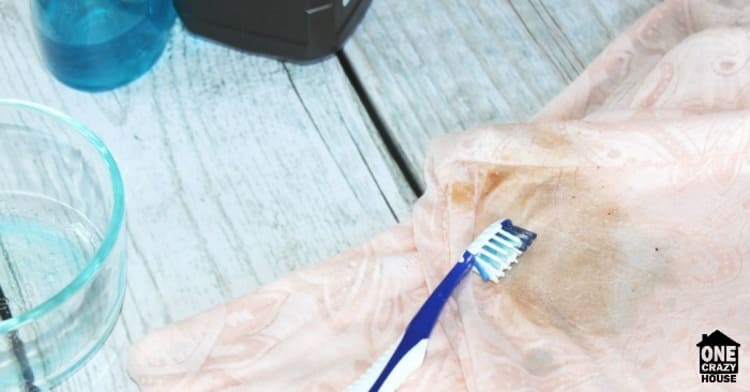 an old toothbrush that has worked on a stain with the homemade cleaner on a pink fabric blouse