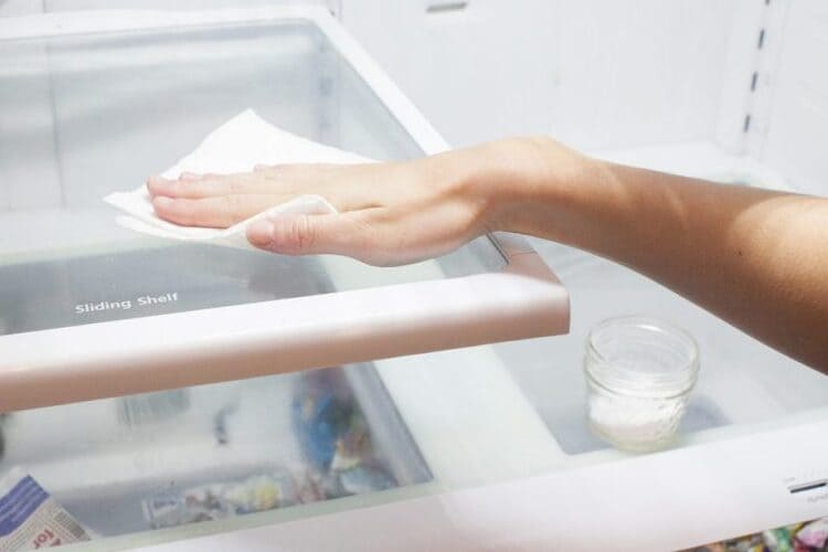 wiping down the inside of the fridge with a cloth to make sure no smells are lurking