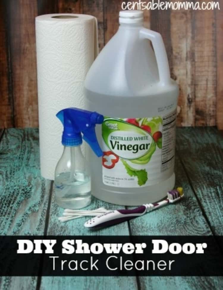 Shower door cleaning tools shown including bottle of vinegar, spray bottle, roll of paper towels, a tooth brush and q-tips