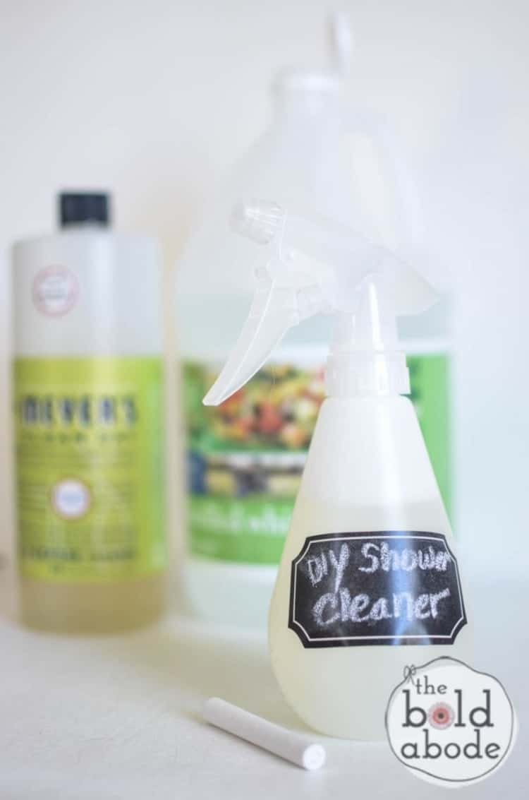 Homemade cleaner in a spray bottle with label that says DIY Shower Cleaner with Mrs. Meyers soap and vinegar in the background
