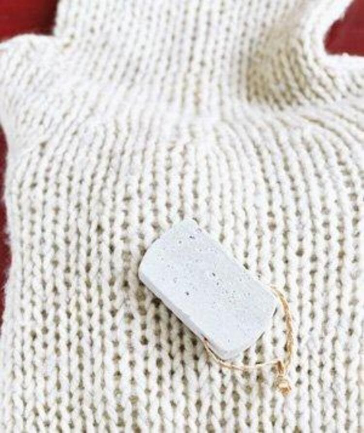 white sweater and pumice stone laying on it