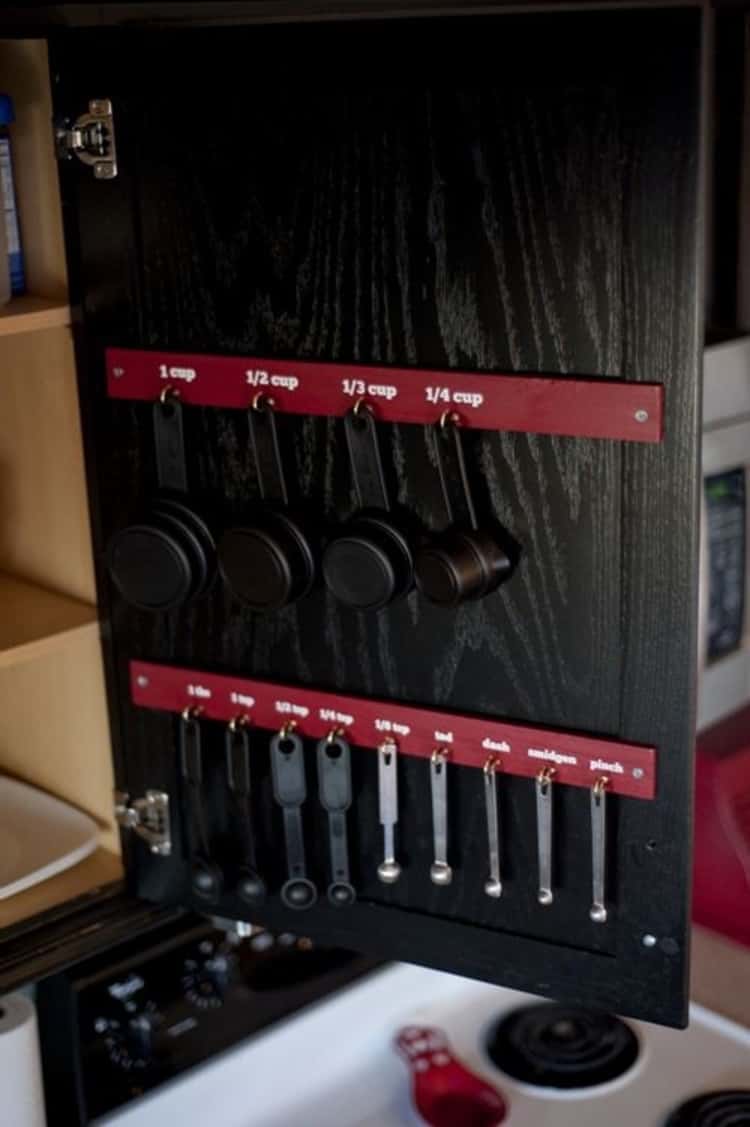 hang measuring spoons and cups on the inside of of a cabinet.