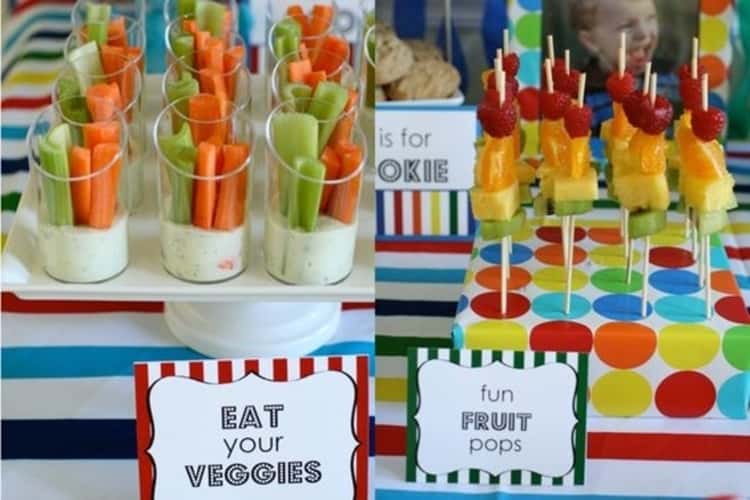 A party table complete with veggies and dip in individual cups for easier serving and colorful fruit pops